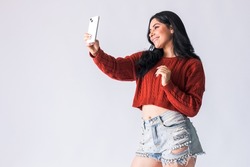 Beautiful Colombian smiling and having fun with her cell phone.  young woman creating content for her social networks with her mobile device. Attractive latin american girl using her mobile phone.
