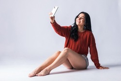 Young woman creating content for her social networks with her mobile device. Attractive latin american girl using her mobile phone. Beautiful Colombian smiling and having fun with her cell phone.