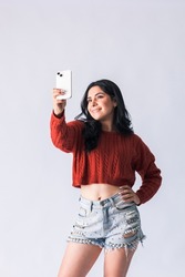 Attractive latin american girl using her mobile phone. Beautiful Colombian smiling and having fun with her cell phone. young woman creating content for her social networks with her mobile device. 