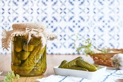 Salted pickled cucumbers preserved canned in glass jar. Plate of pickled homemade gherkins with fresh dill. Autumn vegetables canning. Healthy homemade food. Selective focus.