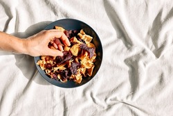 Hand taking crunchy vegetable chips from a plate on the table with linen tablecloth. Veggie snack. Alternative healthy eating. Proper nutrition. Dehydrated vegetables