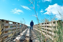 Man tourist walking on old broken wooden bridge over a mountain river