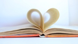 The pages of the book are curved in the shape of a heart with a blurred background. Open book with heart-shaped pages. I love to read. Valentine's day concept. Selective focus.
