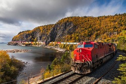 A freight train hauls shipping containers through the rugged landscape.