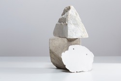Creative minimalist sculpture arrangement on table, random stones and irregular white clay plate composition