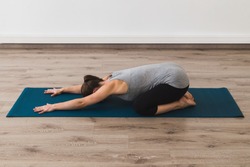 Young woman doing yoga in child's pose