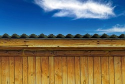 The upper part of the outbuilding on the background of the blue sky with white clouds
