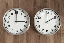 Two clocks, one showing three o'clock, the other showing two o'clock. Time change symbol. Moving the hands backward in autumn to normal time.