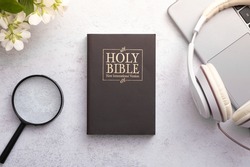 Top View of Holy Bible on working table with headphones. Bible study online concept.
