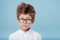 portrait of handsome little boy in glasses look at the camera, isolated on blue background
