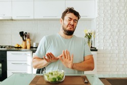 I do not want to eat these vegetables, the young man says with his appearance. She grimaces and shields herself with her hands from the salad bowl. Modern cuisine and trendy food. Stop diet.