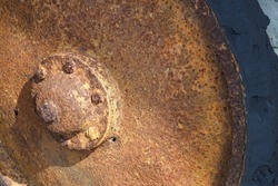An old rusty metal wheel with worn parts of a hard tyre.