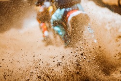 Details of flying debris during an acceleration with mountain bikes race in dirt track in sunshine day time in blurry background. Concept of focus between an accelerate in action sport