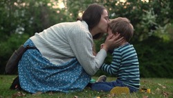 child is crying in park in arms of mom. Mommy soothes baby boy. family mother and child with tears in their eyes. emotionally. loving young mother hugs and soothes her little Son in Park. Motherhood