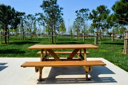 Wooden seat in a city park. Picnic in the park. Rest in the open area. 
Wooden picnic table and seats.
