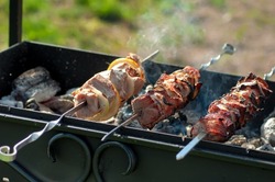 Lots of juicy meat pieces of grilled kebabs. String the pieces of meat on a metal skewer on the grill. The process of cooking kebabs with a lot of smoke. Cooking in nature