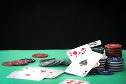 A pair of aces on a deck of playing cards. Poker playing chips on a green table. Online gambling. Addiction. Playing cards and poker chips. Copy space.