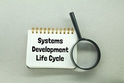magnifying glass and notebooks with the words systems development life cycle