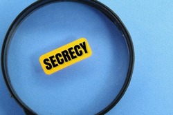 magnifying glass and orange paper with the word secrecy