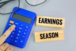 calculator, glasses and a wooden board with the word Earnings Season. Income season concept