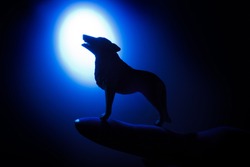 wolf in silhouette howling to the full moon