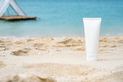 empty cosmetic skin care cream or sun block on sand beach with sea side background travel vacation accessory 