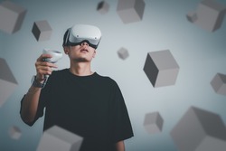 student use vr glasses and looks at empty space with gray background, studio shot.Virtual gadgets for entertainment, work, free time and study. game cyber Virtual reality technology concept.
