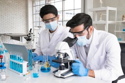 Health care researchers working in life science laboratory. Male research scientist and supervisor preparing and analyzing microscope slides in research lab. The invention of the coronavirus vaccine.