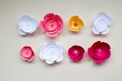 Handmade paper flowers on paper background, white and pink roses, decor for invitation 