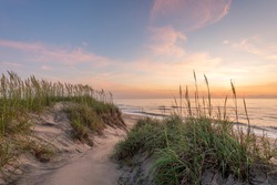 A picture sand dunes covered in marram grass during a beautiful sunrise in the Outer Banks, North Carolina. 