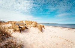 Bench on a beautiful white sand beach in south Sweden. Popular tourist destination.
