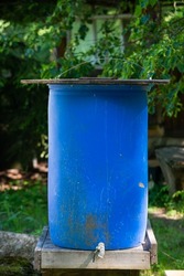 huge blue water barrel for washing hands at a rural tourism campsite.