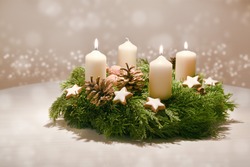 Third Advent - decorated Advent wreath from evergreen branches with white burning candles, tradition in the time before Christmas, warm background with festive bokeh and copy space, selected focus