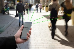Smart phone with Corona Warn App, a contact tracking or tracing application against Covid 19 pandemic is connecting other phones from moving people in the city to analyze the risk of infection