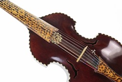 Part of a viola d amore from dark wood decorated with inlays and a carved sound hole, the musical string instrument was used mainly in the baroque period, isolated on a white background
