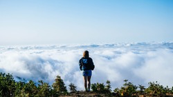 
Young girl on top of a mountain peak gazing at the views over a blanket of clouds. Alone in the middle of nature, with the feeling of purity, peace and tranquility, of disconnection with the world. L