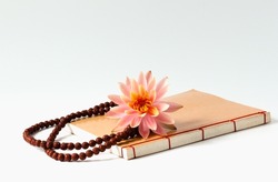 The Buddhist book, the Buddhist rosary and a pink lotus flower 