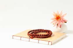 The Buddhist book, the Buddhist rosary and a pink lotus flower in vase
