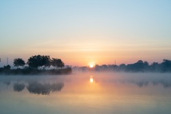 Morning time on the lake and mist fog.The trees and foggy with sun rise sky and reflective in the water.Natural landscape in the morning time.