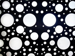 White circles on a black background, a lamp on a black ceiling, light through metal. Abstract background