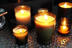 Many glass of scented aromatic candles are lighting in the dark living room 