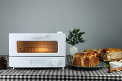 white modern design toaster oven is on the table with homemade sweet potato butter toast breads on grey cement wall background in the kitchen room for breakfast