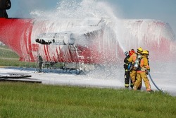 team of firefighters spraying foam during aircraft training