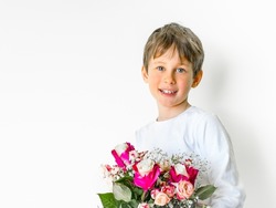 Portrait of an eight-year-old Caucasian boy with a bouquet of flowers in his hands looking into the distance. Greeting card mockup with copy space