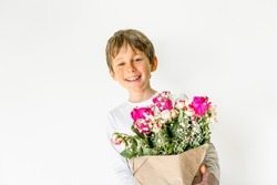 Charming boy with a bouquet of flowers in his hands smiles. Greeting card mockup with copy space. Portrait of a boy 8 years old, white, caucasian
