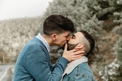 Gay couple in love kissing at the forest in winter