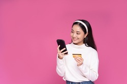 Beautiful Asia women smile use smartphone and credit card purchase online shopping and excited with success payment on isolated pink background