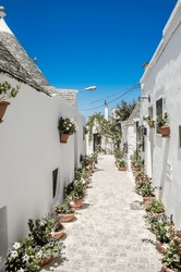 Alley with flowers in Alberobello, Italy.