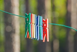 Color clothespins. Pins hanging on rope. Drying clothes outdoor. Clothes peg clips for clothes on the line. Washing concept, closeup, soft focus