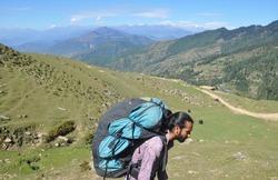 Side view of a male tourist carrying parachute backpack, walking in beautiful mountain of Himachal Pradesh 